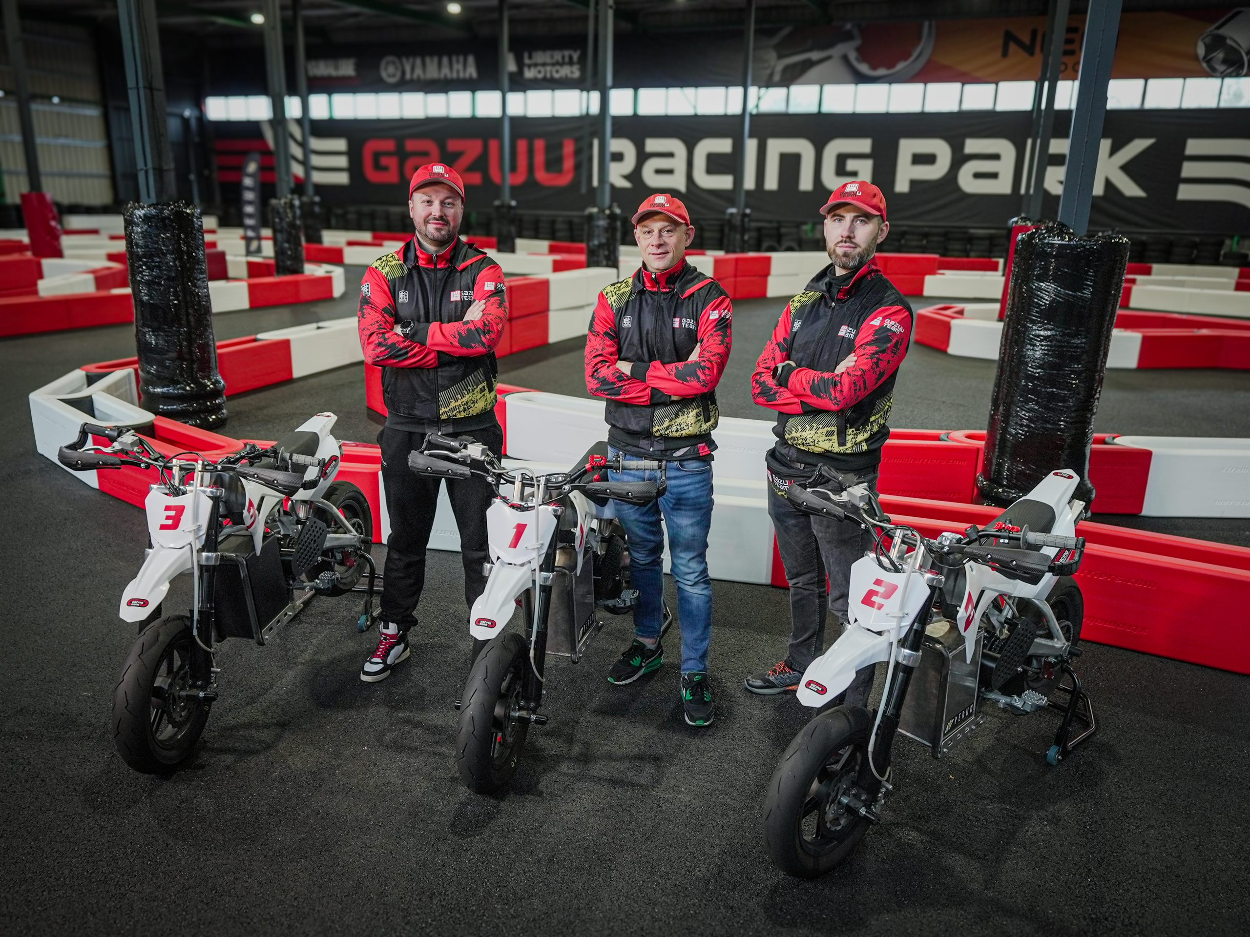 Trzej właściciele Gazuu Racing Park przy elektrycznych pitbike'ach, w tle baner z nazwą toru